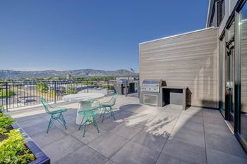 A patio with a table and chairs overlooks a mountainous landscape.